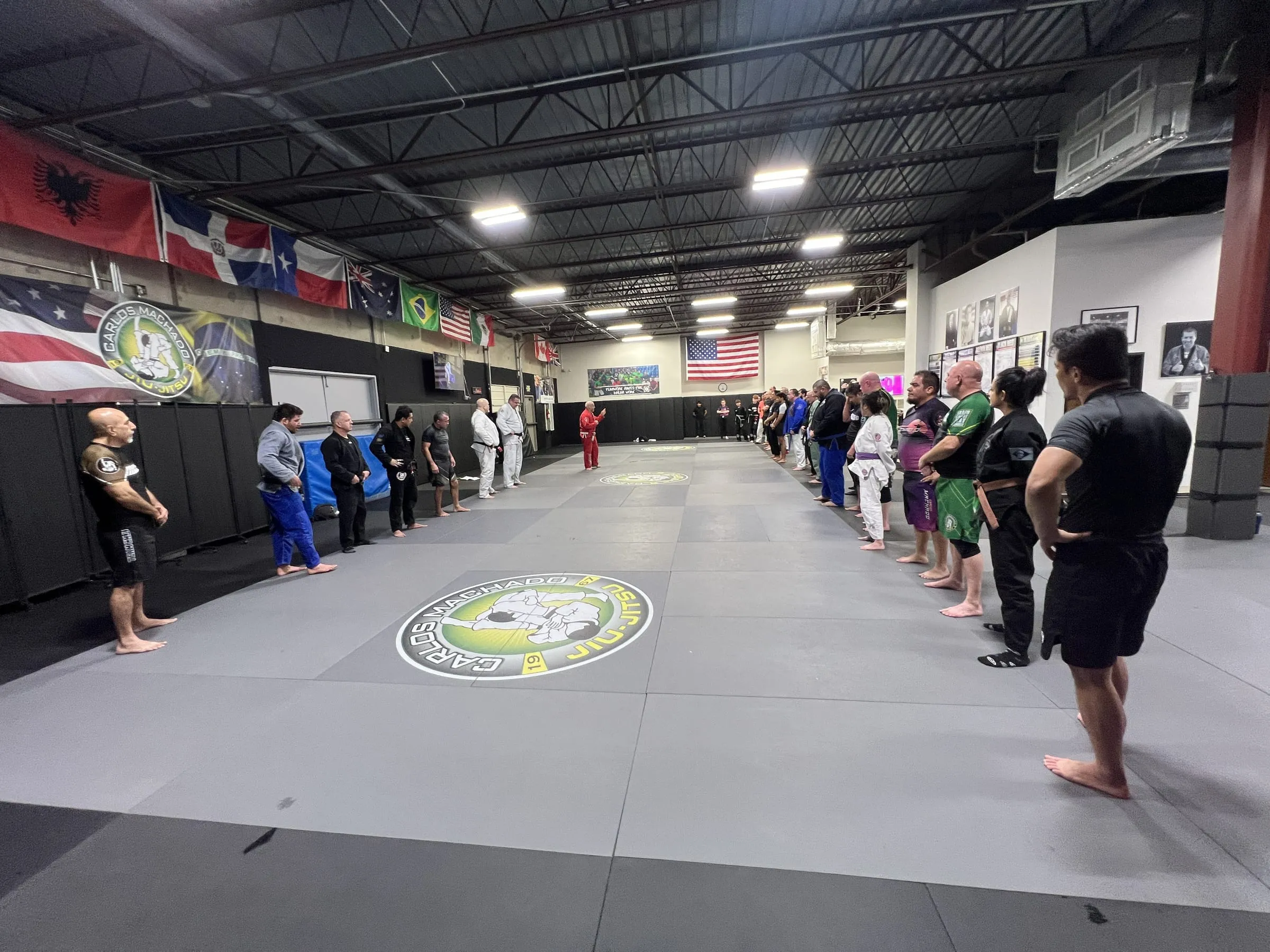 A Machado Method class lined up on the mat under the Carlos Machado Jiu-Jitsu logo in Carrollton, TX